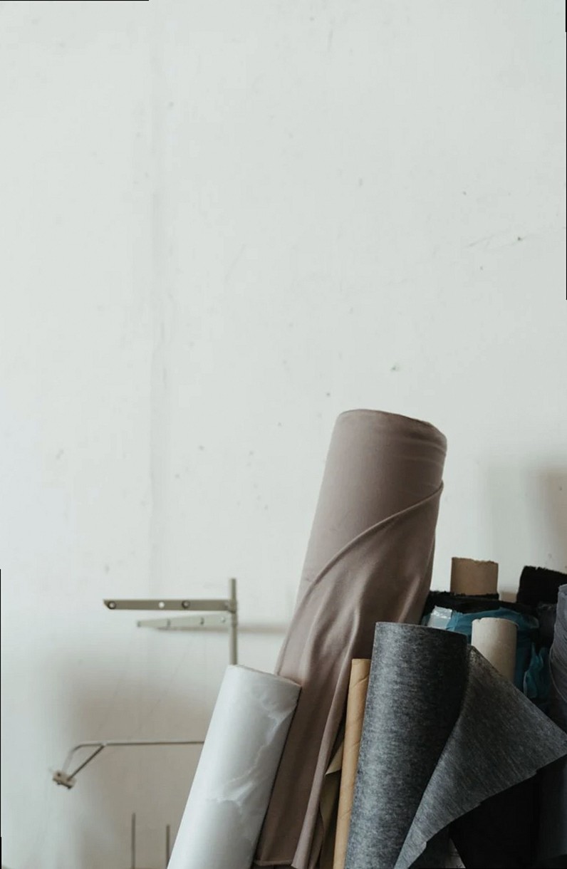 Fabric rolls stacked in an atelier creating a minimalist, craft-inspired scene.